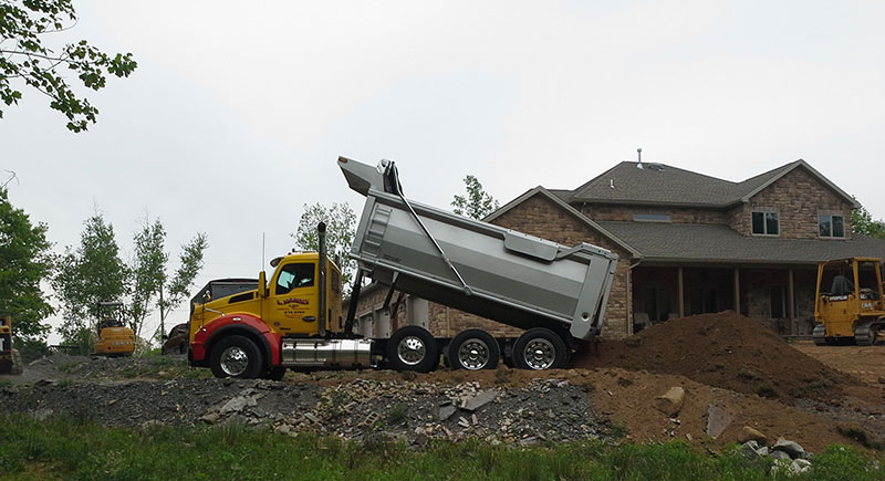 A picture of L.Marki & Son, Inc. delivering top soil and spreading it for a customer
