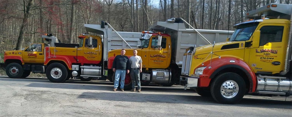 Photo of Bob and Rob Marki in front of a fleet of their trucks