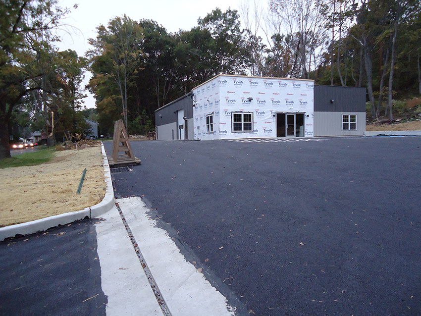 A picture of the building with freshly paved parking lot and areas seeded for grass